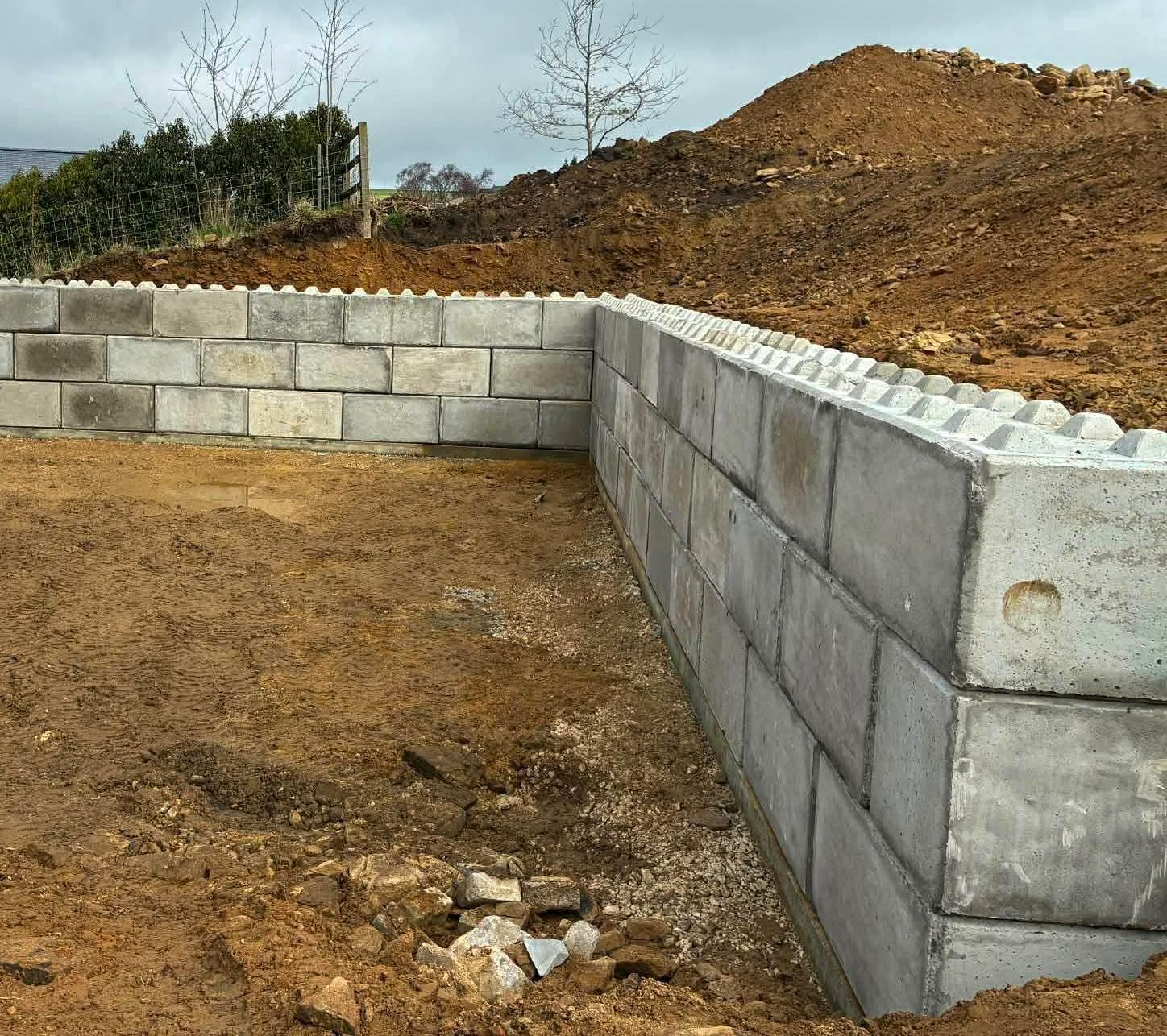 Long interlocking concrete block wall with a return, built on site