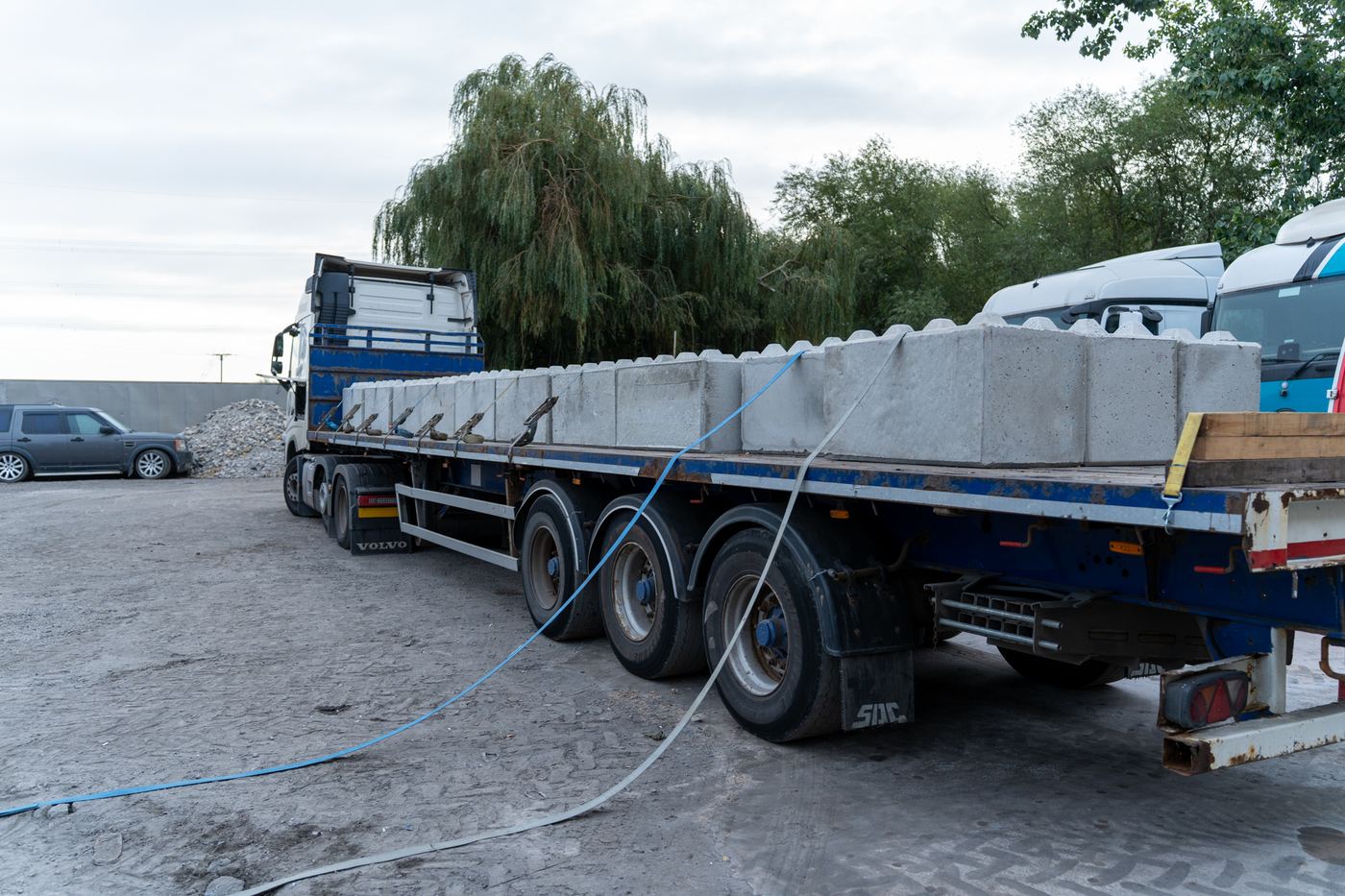 Flatbed trailer loaded with interlocking concrete blocks, strapped and ready to leave the yard