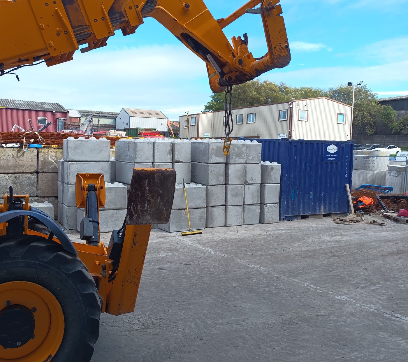 Telehandler with a lifting hook in front of interlocking blocks stacked on site
